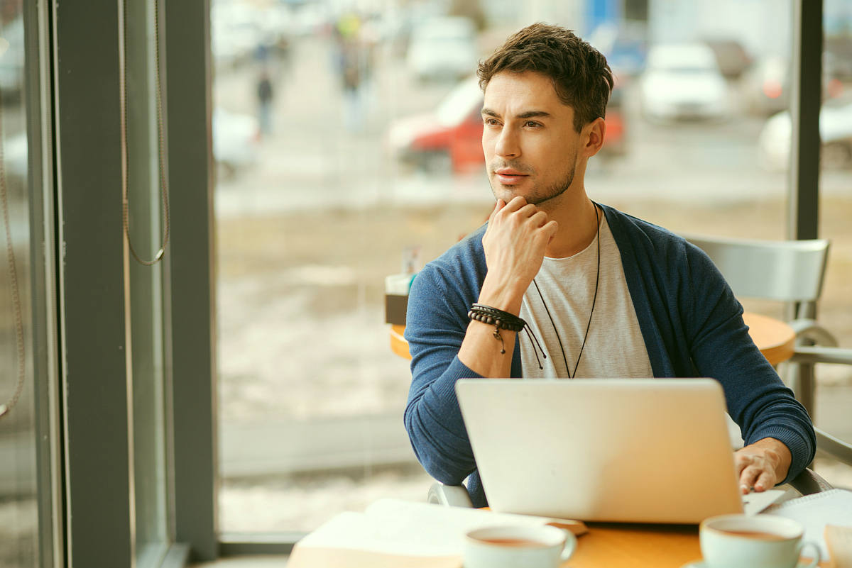 Handsome young guy holding hand on his chin and thoughtfully looking | How To Re-Evaluate Your Relationship With Social Media To Live More Intentionally