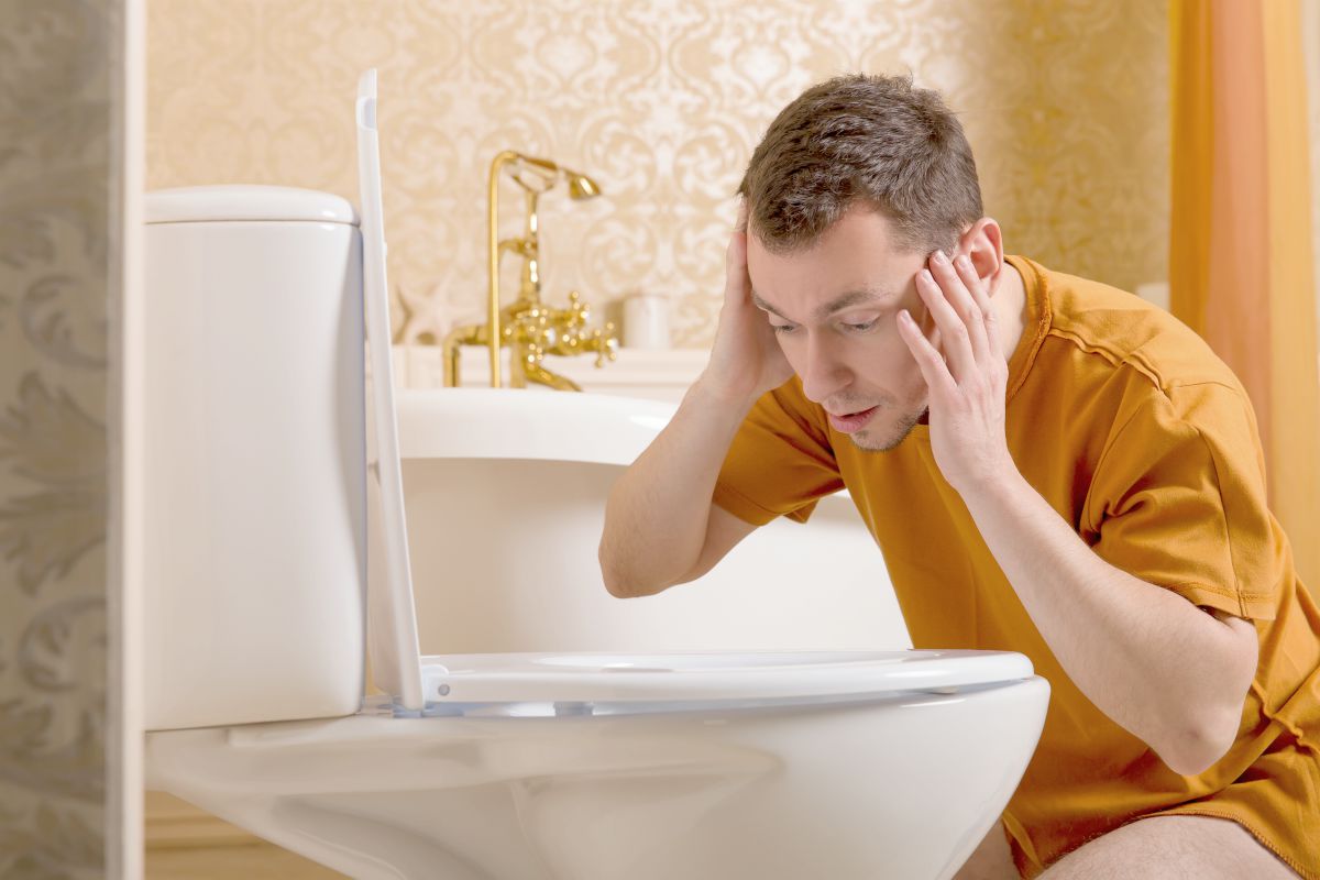 suprised man looking inside toilet bowl | Things Your Poop Color Is Telling You About Your Gut Health | poop