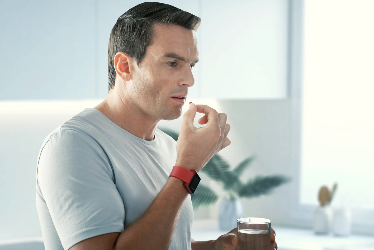 Taking pills handsome young man standing | Leaky Gut: 9 Tips On How To Heal It Naturally