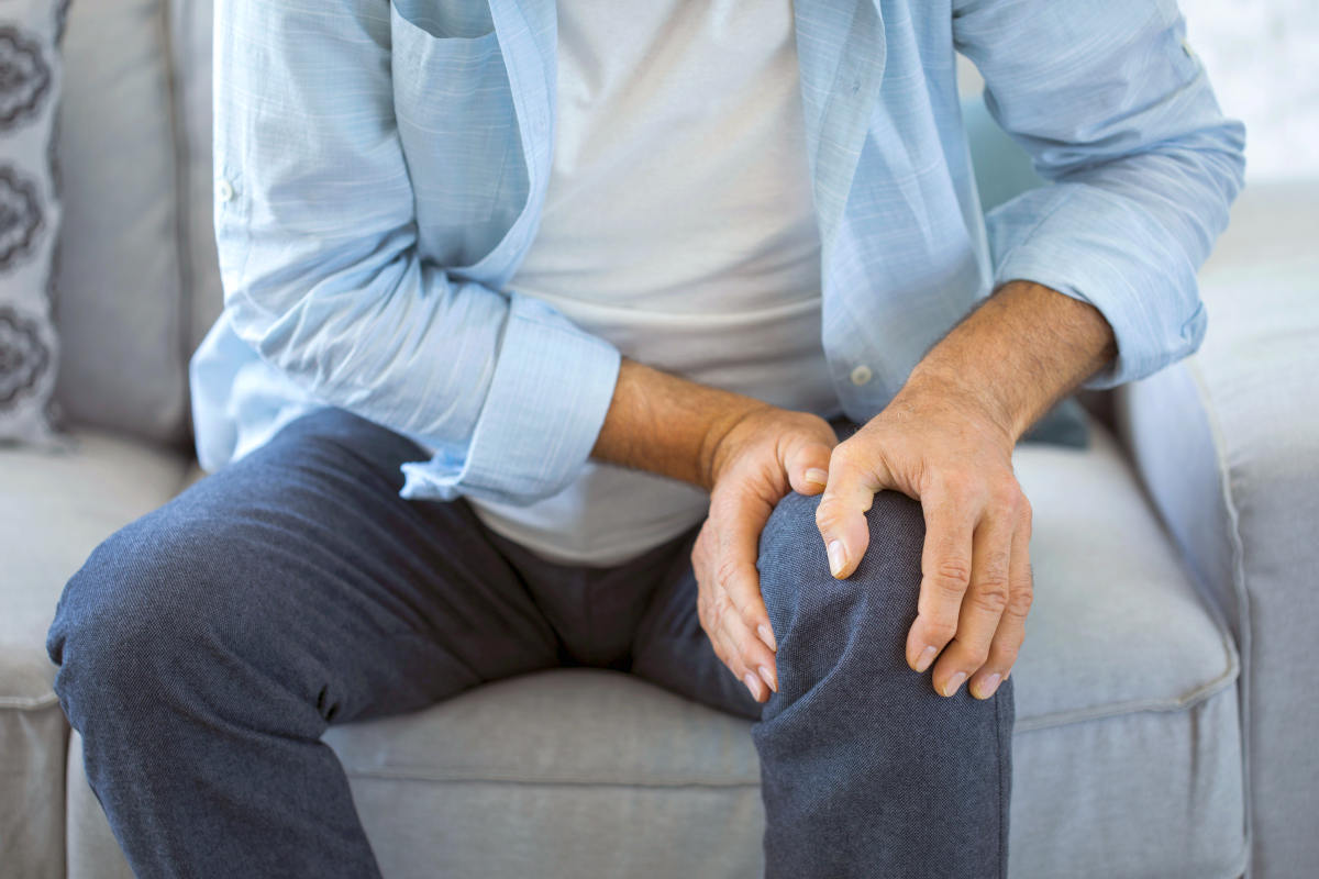 Old man suffering from knee pain sitting sofa | Can Too Much Protein Cause Inflammation?