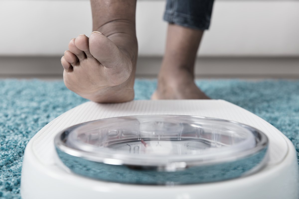 person stepping on weighing scale | The Amount Of Caffeine In Tea, Coffee, And Soda | FAQ | caffeine in tea | caffeine pills